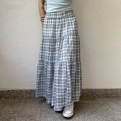 Person wearing a long plaid skirt with a plain background