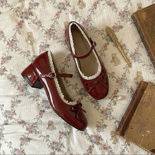 Red shoes with white laces on a floral-patterned surface with books and a quill.