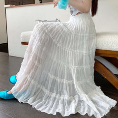 Woman wearing a white dress with ruffled layers in an indoor setting.