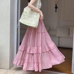 Woman wearing a pink tiered skirt holding a white textured bag in a living room.