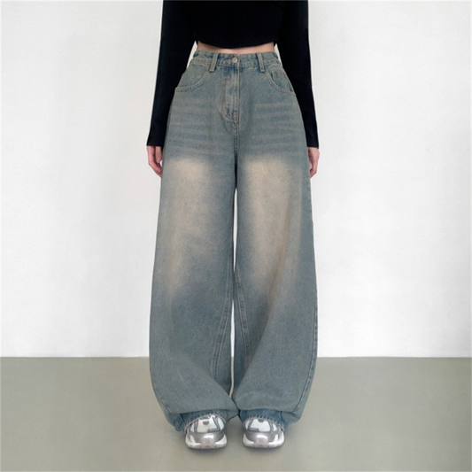 Person wearing high-waisted blue jeans and a black top on a plain background