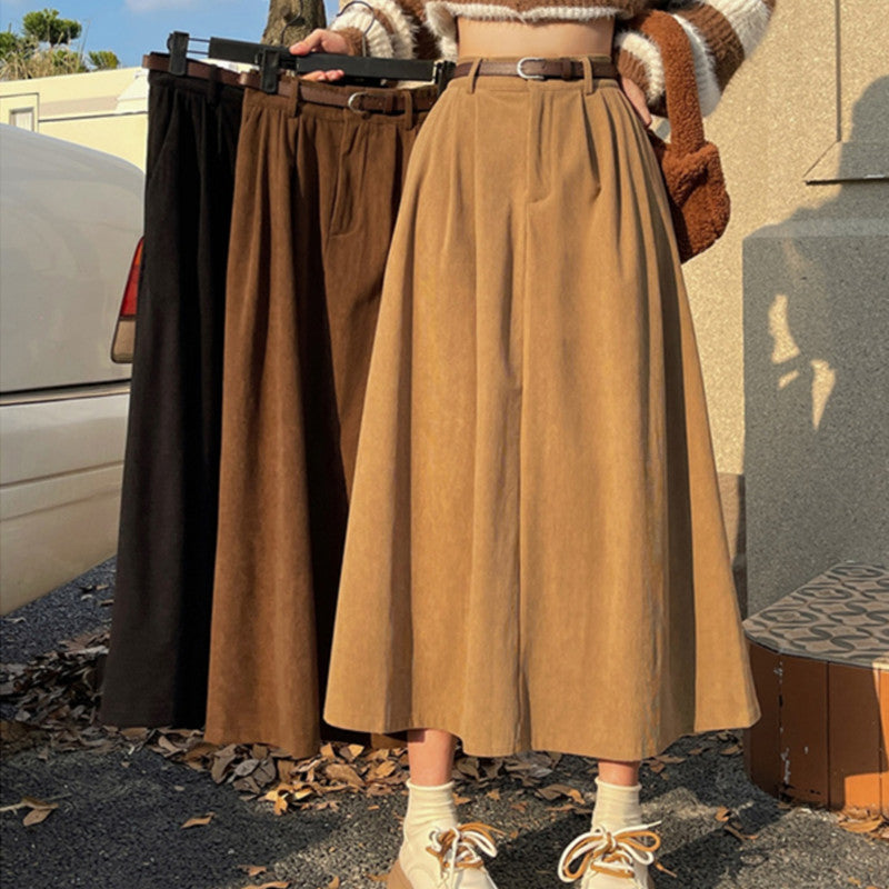 Person holding three long skirts in different colors outdoors.