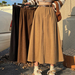 Person holding three long skirts in different colors outdoors.