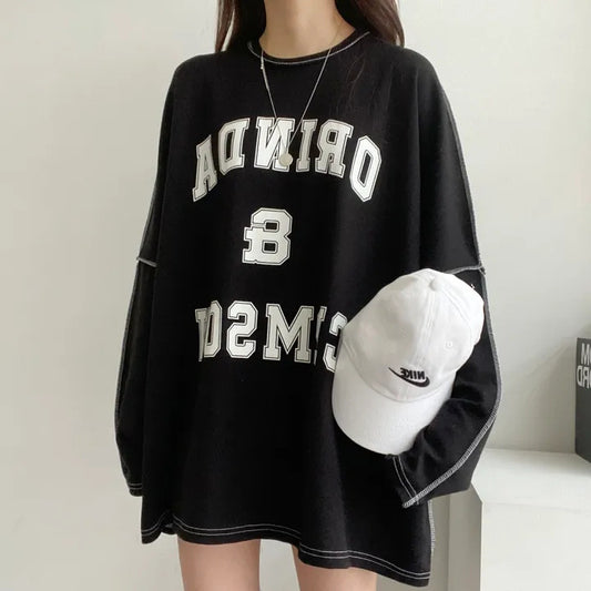 Black oversized sweater with white text and a white cap on a neutral background