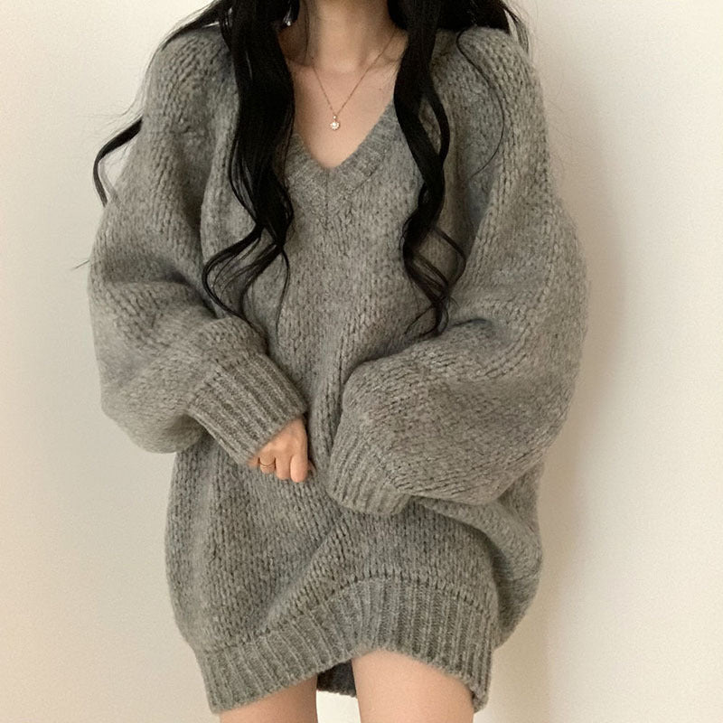 Person wearing a gray oversized sweater against a plain background
