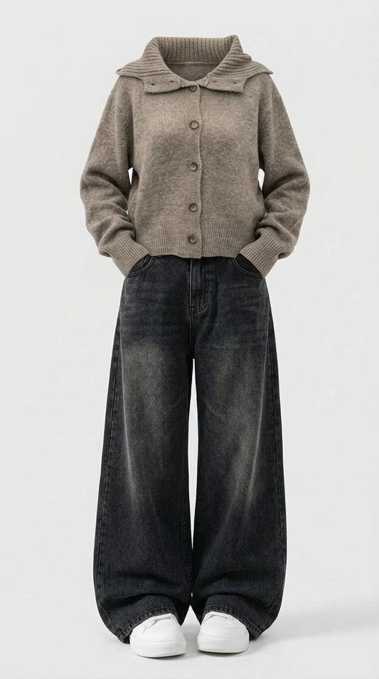 A person wearing a taupe knit button-front cardigan with a wide collar, dark washed wide-leg jeans, and white sneakers, standing against a light gray studio background.