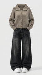 A person wearing a taupe knit button-front cardigan with a wide collar, dark washed wide-leg jeans, and white sneakers, standing against a light gray studio background.