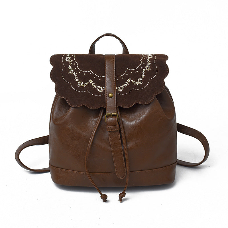 Brown leather backpack with lace detailing on a white background