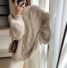 Person wearing a beige cable knit sweater taking a mirror selfie.