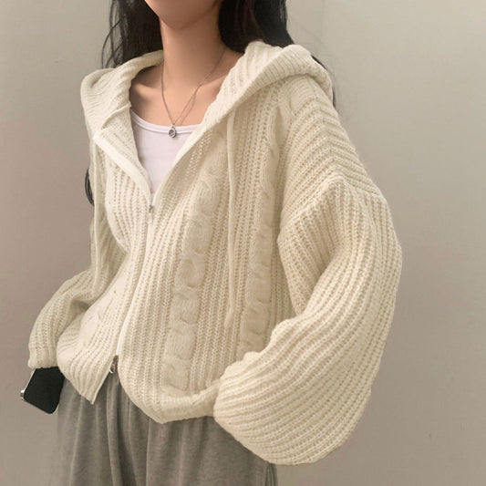 Person wearing a cream knitted cardigan against a plain background