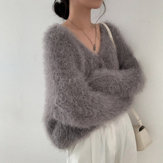 Person wearing a fluffy gray sweater against a plain background