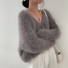 Person wearing a fluffy gray sweater against a plain background