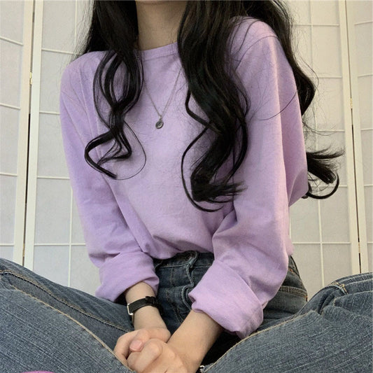 Person wearing a light purple sweatshirt sitting on a tiled floor.