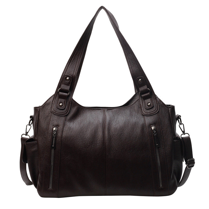 Black handbag with multiple pockets and straps on a white background