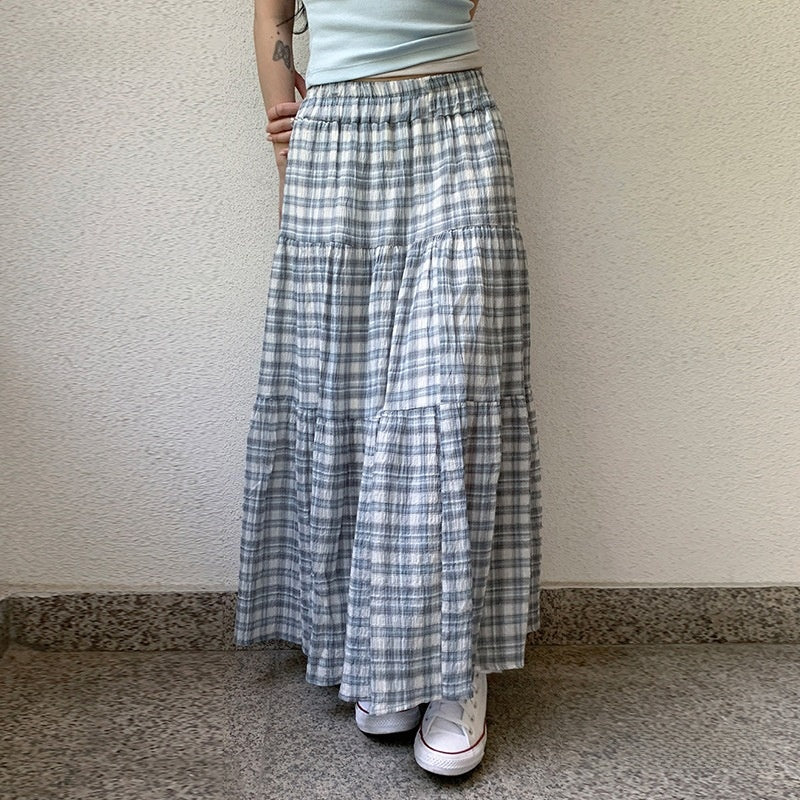 Person wearing a long plaid skirt with a plain background