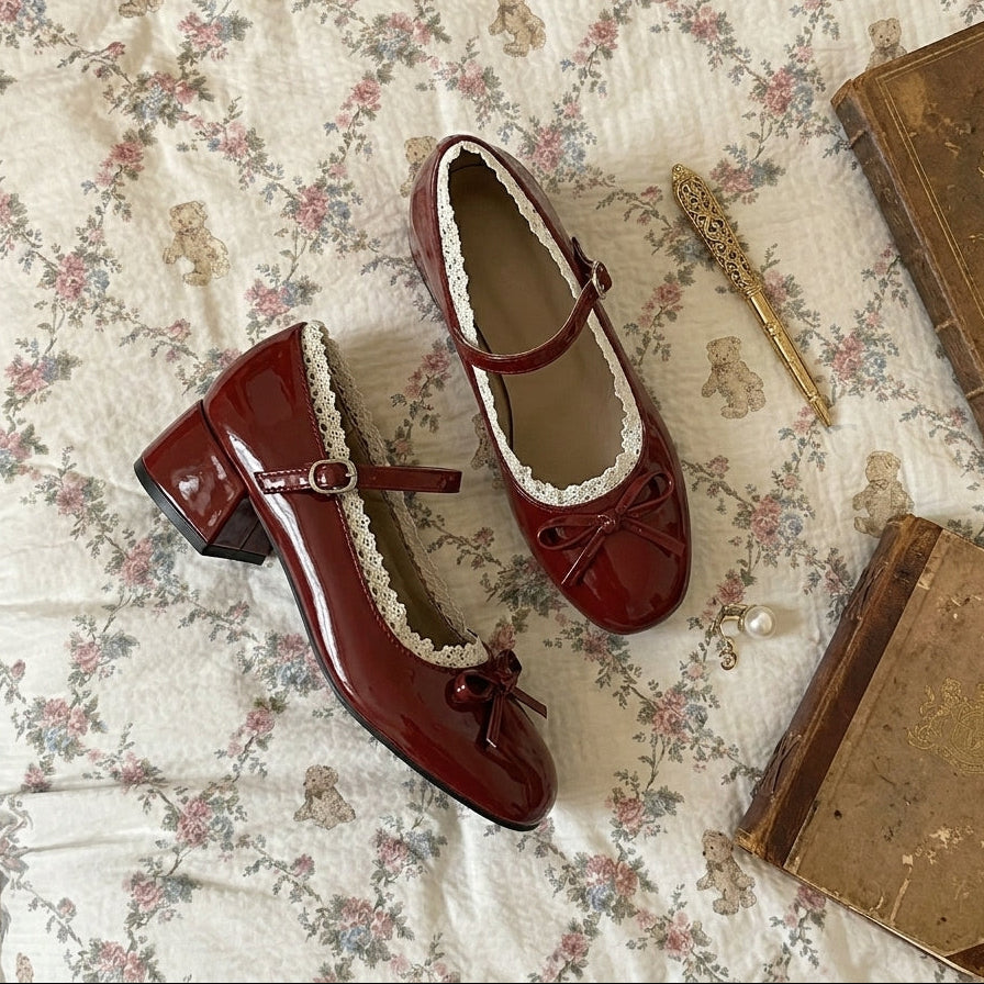 Red shoes with white laces on a floral-patterned surface with books and a quill.
