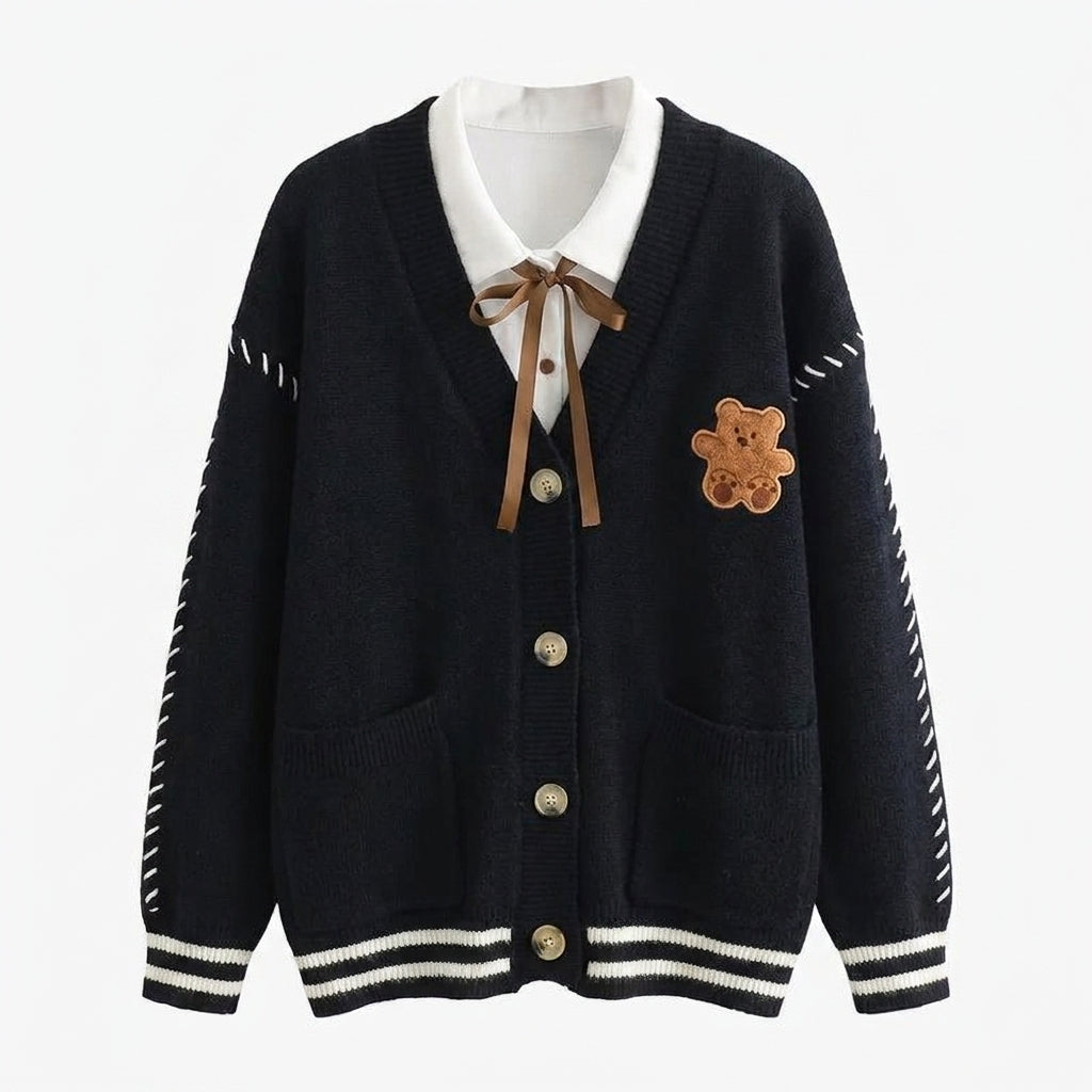 Black cardigan with white collar, buttons, and teddy bear patch on a white background