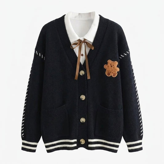 Black cardigan with white collar, buttons, and teddy bear patch on a white background