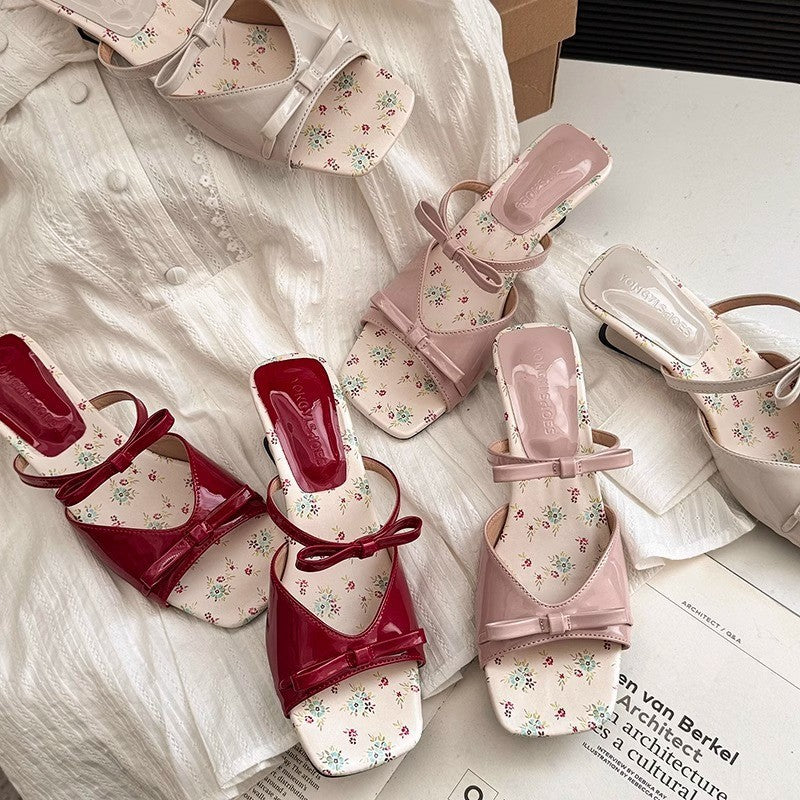Pair of red and pink floral shoes on a white fabric background