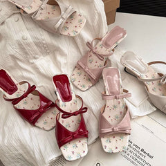 Pair of red and pink floral shoes on a white fabric background