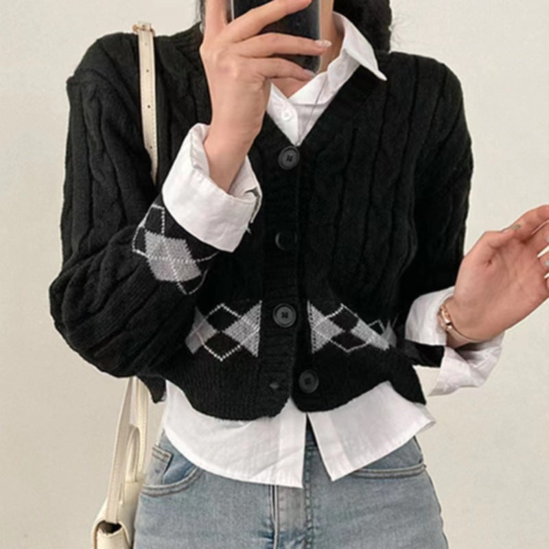Person wearing a black cable knit cardigan over a white shirt with a geometric pattern.