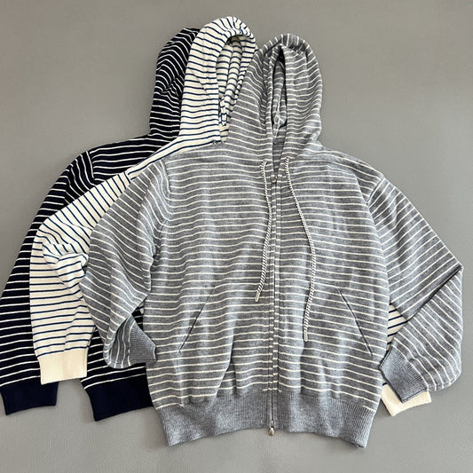 Three striped zip-up hoodies are laid flat on a gray background. The front hoodie is heather gray with thin white stripes, and the two hoodies behind it are navy and white striped.