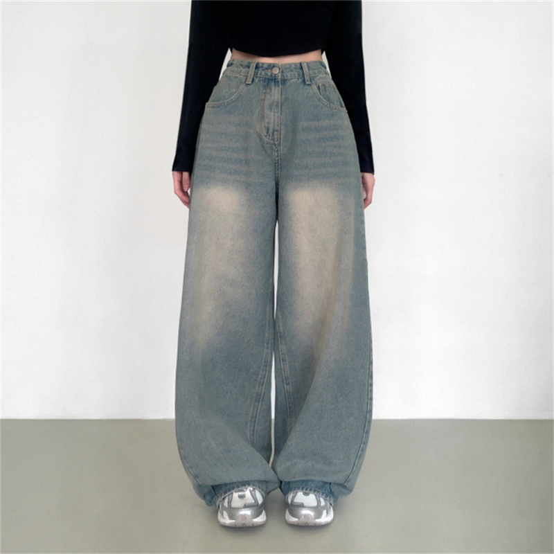 Person wearing high-waisted blue jeans and a black top on a plain background