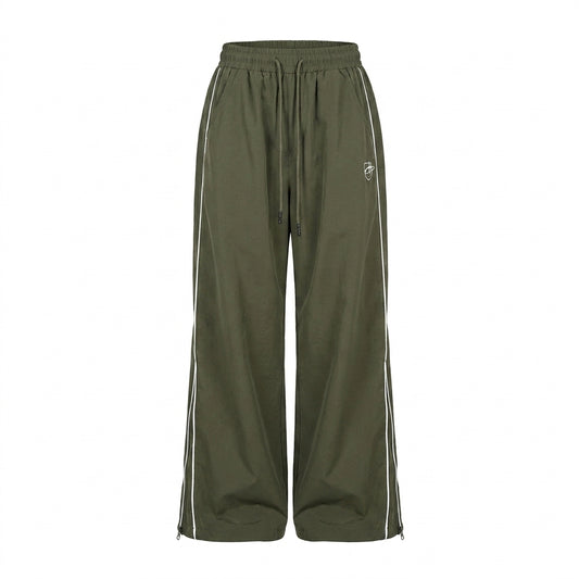 Green track pants with white stripes on a white background