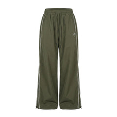Green track pants with white stripes on a white background