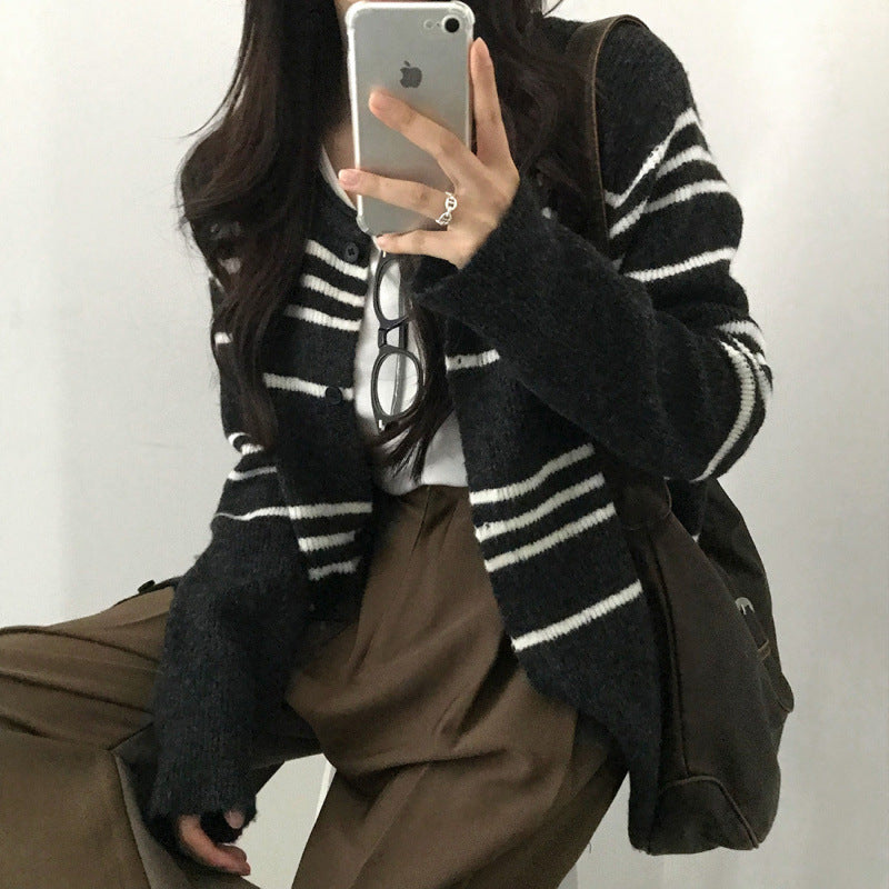 Person wearing a black and white striped cardigan with a plain background