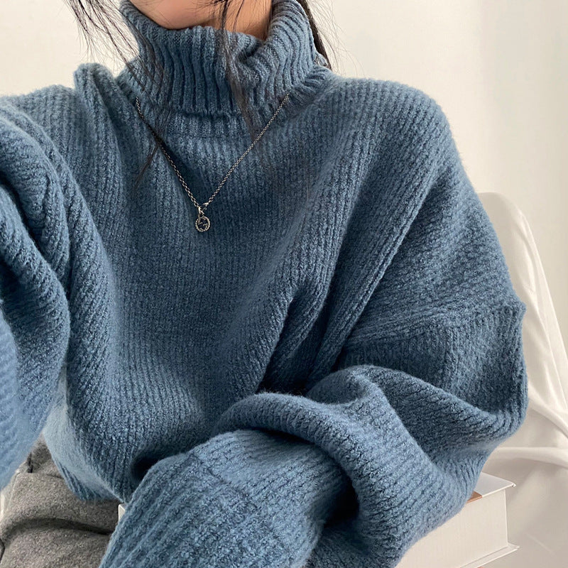 Close-up of a person wearing a blue knitted sweater with a neutral background