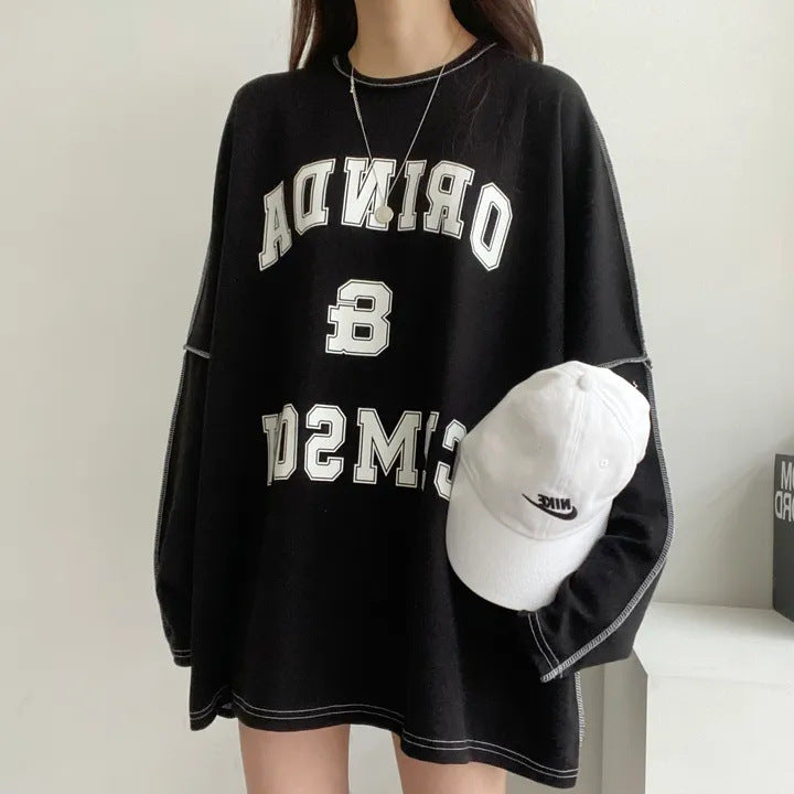 Black oversized sweater with white text and a white cap on a neutral background