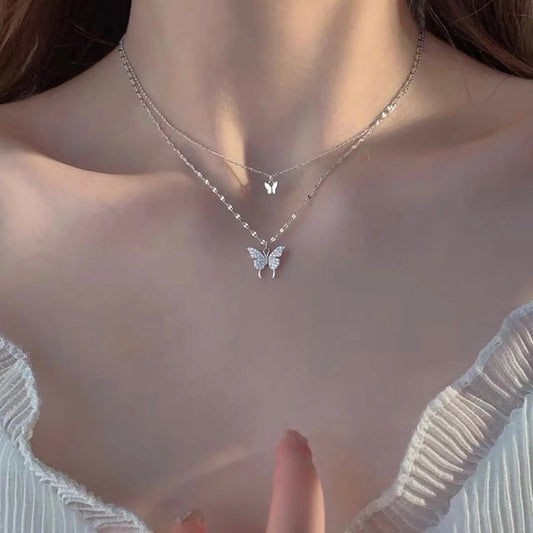 Butterfly necklace on a person wearing a light-colored top.