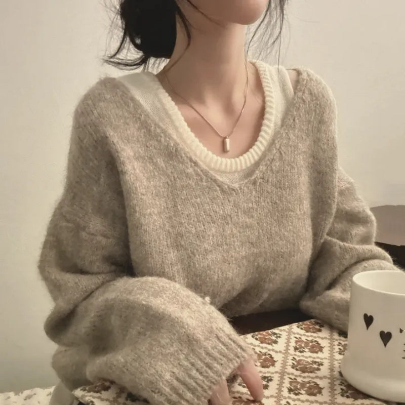 Person wearing a beige sweater sitting at a table with a white mug.