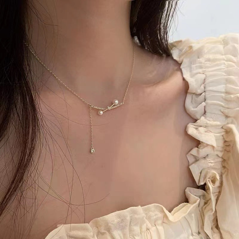 Necklace with pearl pendants worn by a person against a neutral background