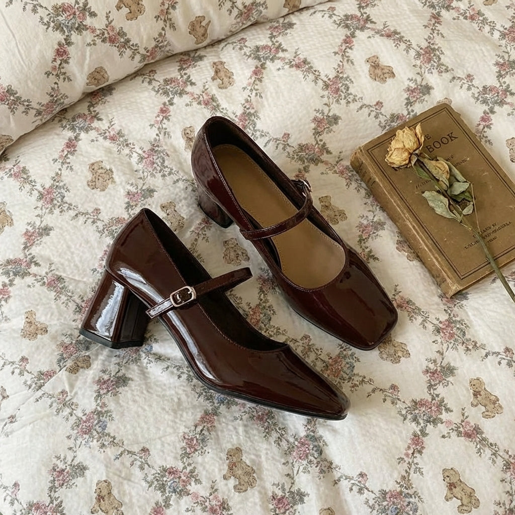 Brown patent leather shoes with a strap on a floral bedspread