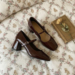 Brown patent leather shoes with a strap on a floral bedspread