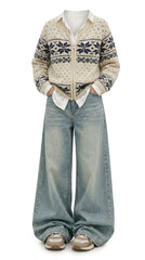A person wearing a cream knit zip-front cardigan with a navy Fair Isle pattern, styled with light-wash wide-leg jeans and beige sneakers against a plain white background.