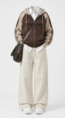 A mannequin styled with a brown and beige zip-up hoodie featuring 'LOFTY UNDER' text on the chest, cream wide-leg pants, a dark brown shoulder bag, and white sneakers, set against a plain light gray background.