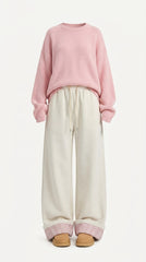 A model wearing a pink crewneck knit sweater and cream wide-leg sweatpants with a pink gingham cuff, paired with tan shoes, against a plain white background.