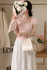 Woman in a pink top and white skirt holding flowers in a store setting.