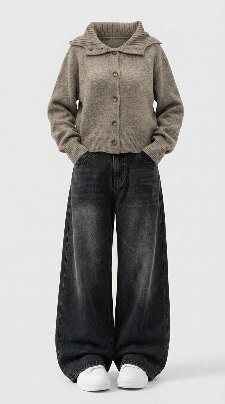 A person wearing a taupe knit button-front cardigan with a wide collar, dark washed wide-leg jeans, and white sneakers, standing against a light gray studio background.