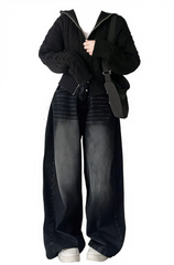Person wearing a black outfit with wide-leg jeans and a black jacket on a white background