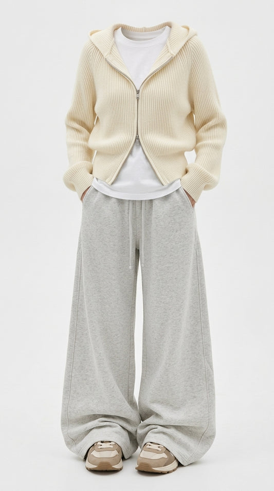 A model wearing a cream ribbed zip-up hooded cardigan over a white t-shirt, paired with light gray wide-leg sweatpants and beige sneakers, against a plain white studio background.