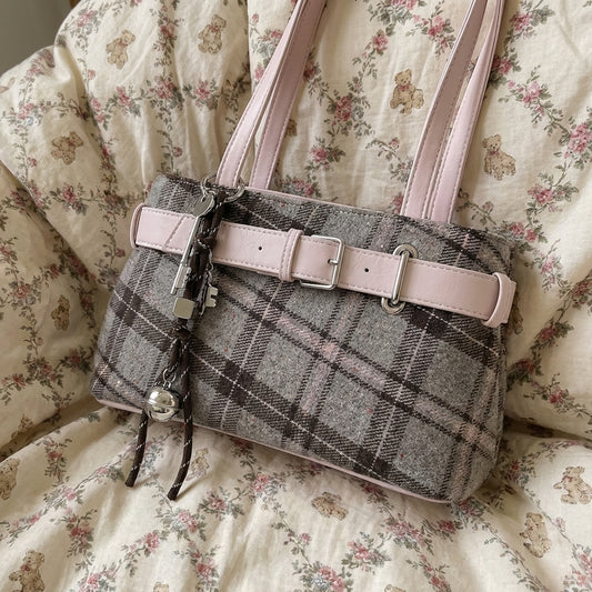 Plaid handbag with pink strap on a floral-patterned fabric background