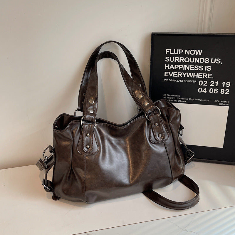 Brown leather handbag on a light surface with a framed quote in the background.