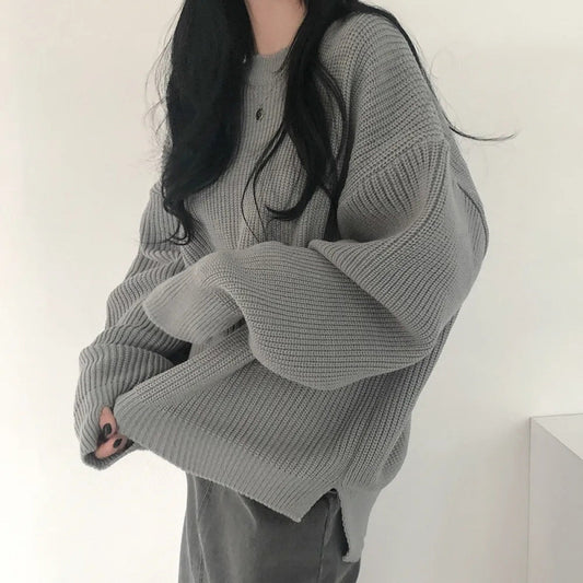 Person wearing a gray oversized sweater against a white background