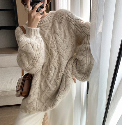 Person wearing a beige cable knit sweater taking a mirror selfie.