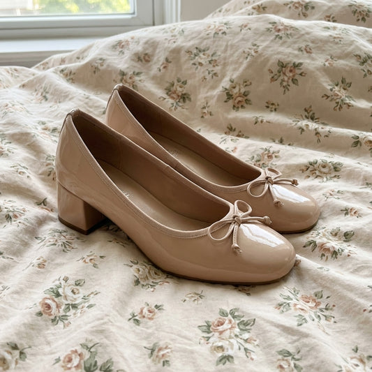 Pair of beige shoes with a bow on a floral bedspread