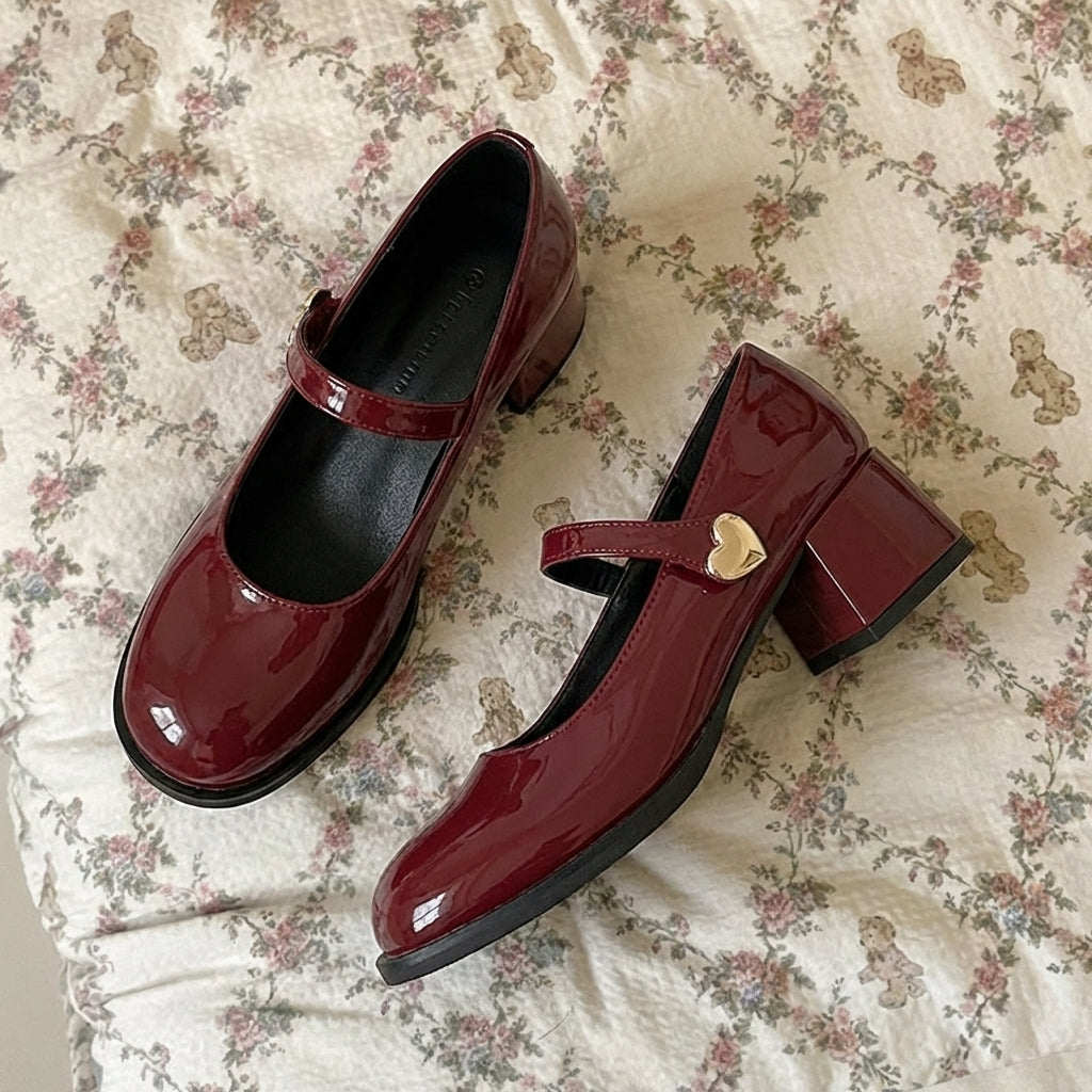 Red patent leather shoes with a heart-shaped buckle on a floral fabric background